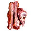 Delumani smoked homemade meat slices, a variety of flavorful cured meats on a wooden board with herbs and bread.